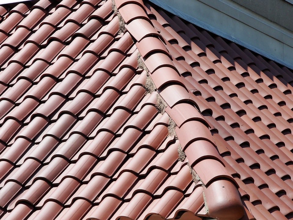 Close-up of red Spanish-style clay S-tiles with a mortared hip ridge